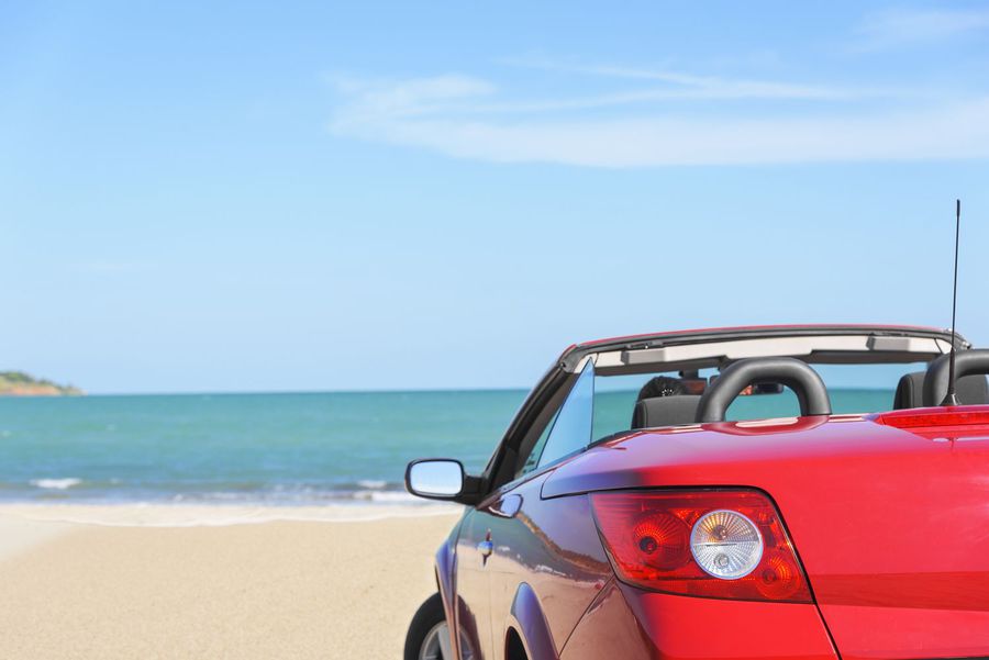 Summer car trip vacation . Woman in red car at background of sea water. Travel ,freedom and holidays concept.