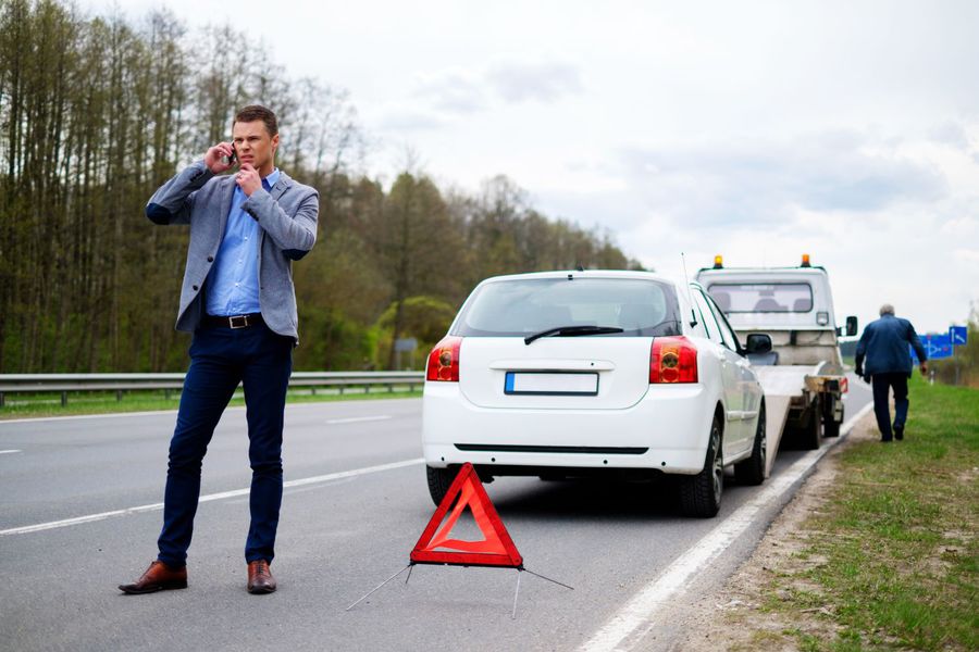 Man calling while tow truck picking up his broken car Man calling while tow truck picking up his broken car.