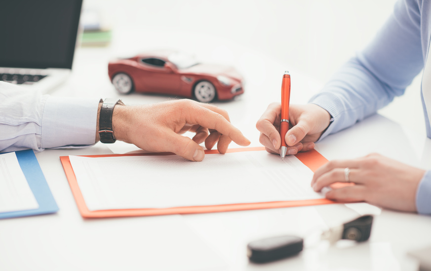 Driver signing a car insurance Woman signing a car insurance policy, the agent is pointing at the document